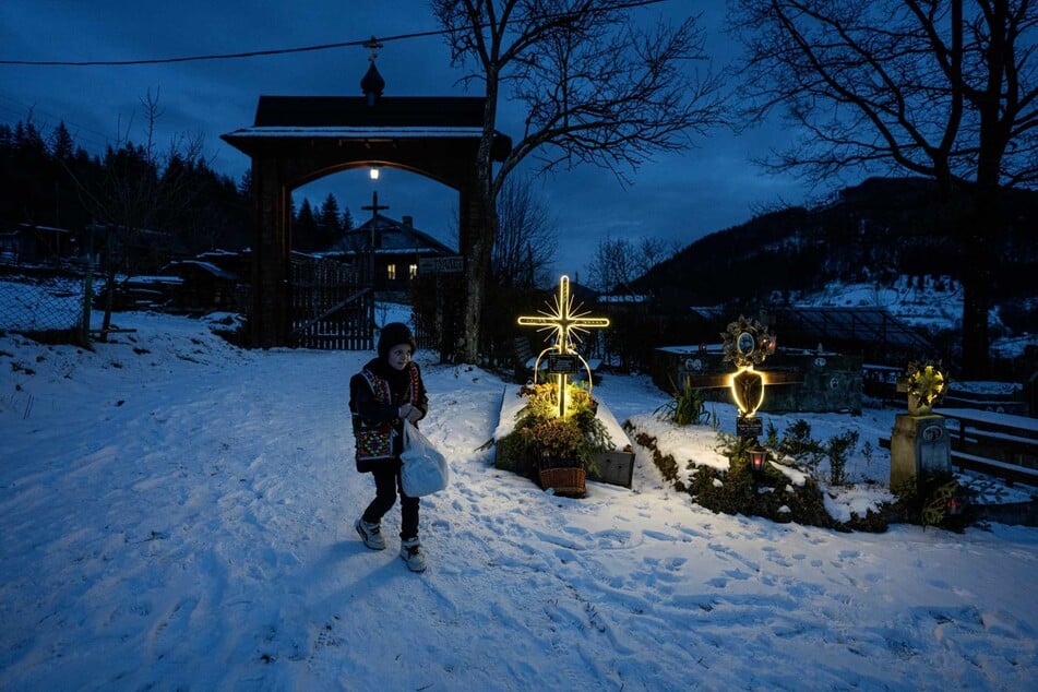 Ein Junge geht nach dem Weihnachtsgottesdienst auf dem Friedhof des Dorfes Kryworiwnja durch den Schnee. Russland attackiert ungeachtet der Feiertage die Menschen in der Ukraine.