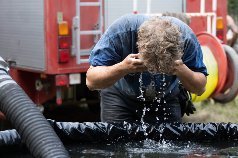 Ein Feuerwehrmann erfrischt sich mit Löschwasser.