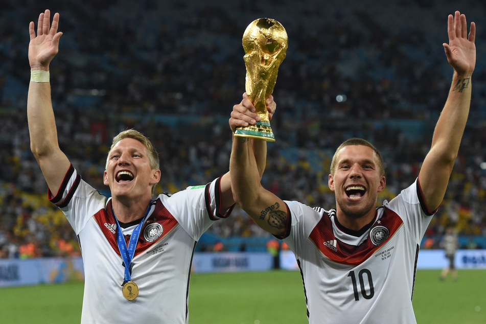 Bastian Schweinsteiger (39, l.) und Lukas Podolski (38) jubeln nach dem Sieg der FIFA Weltmeisterschaft 2014 in Brasilien mit dem Pokal.