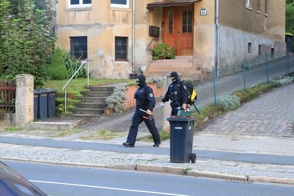 Vermummte Einsatzkräfte durchsuchen ein Gebäude.