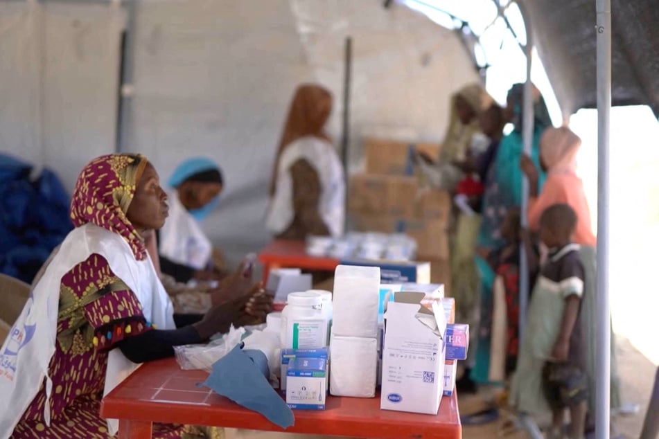 A medic waits in a makeshift clinic in Tawila, Sudan, as displaced people gather after fleeing El-Fasher city in Darfur, on October 29, 2025.