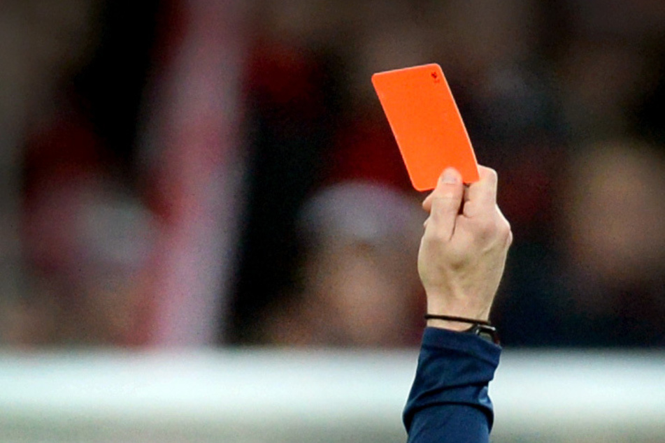 Ein Schiedsrichter zeigt einem Fußballspieler die Rote Karte (Symbolbild).