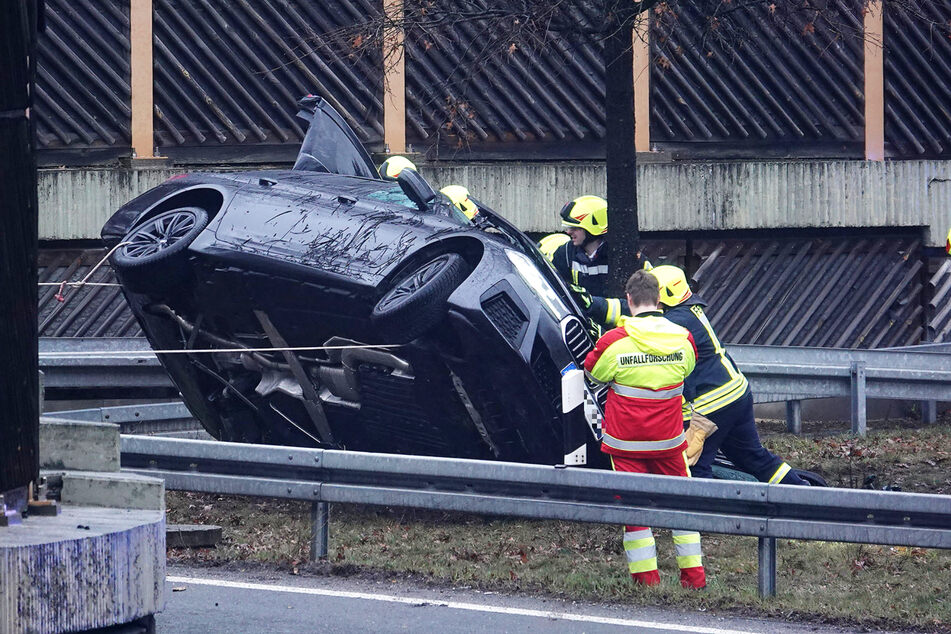 Vier Feuerwehrleute kippen den auf die Seite geschleuderten BMW wieder in eine aufrechte Position.