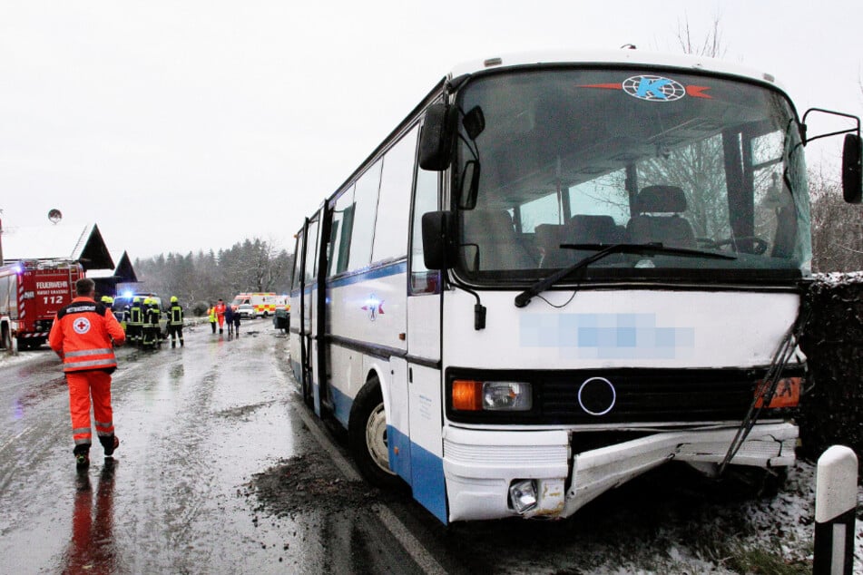 Der beschädigter Schulbus steht an der Unfallstelle.