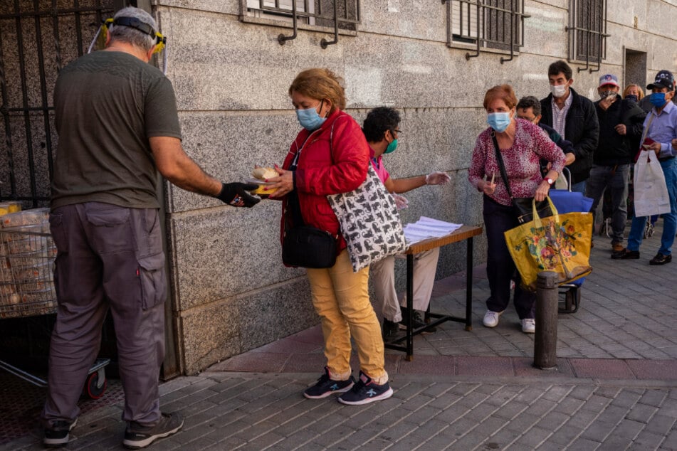 Madrid: Menschen stehen Schlange vor dem Sitz eines katholischen Ordens inmitten der Corona-Pandemie, weil dort Freiwillige Lebensmittel verteilen.
