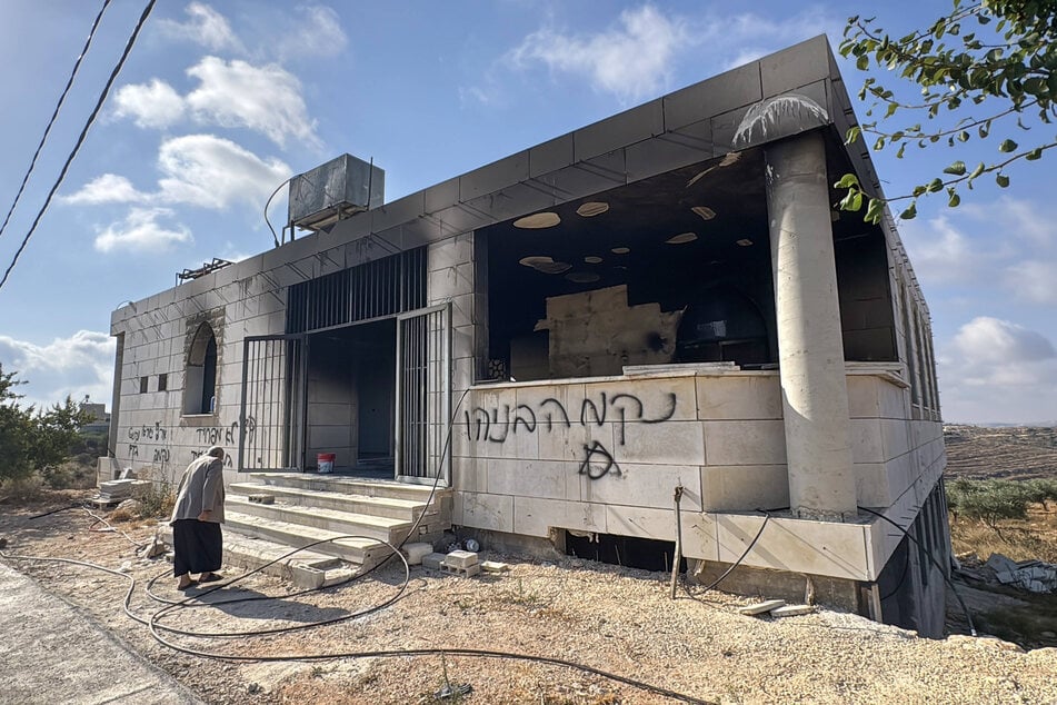 A Palestinian resident inspects fire damage and graffiti at Al-Rahmah Mosque after an arson attack by Israeli settlers in the village of Qusra, south of Nablus in the occupied West Bank, on July 26, 2026.