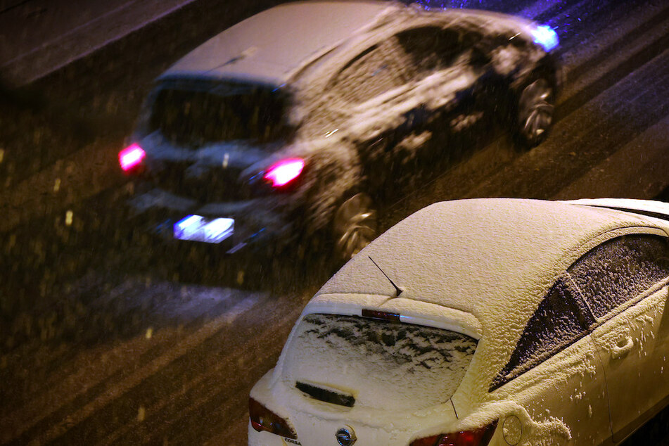 Autos fahren durch das Schneetreiben in Würzburg.