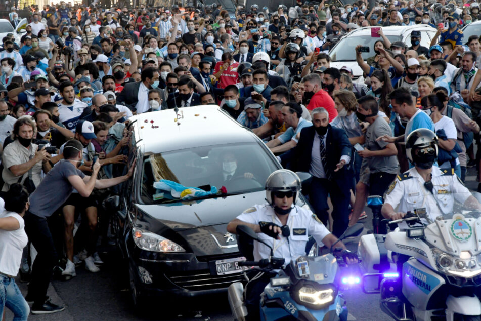 Der Leichenwagen mit den sterblichen Überresten von Diego Maradona verlässt das Regierungsgebäude begleitet von Fans
