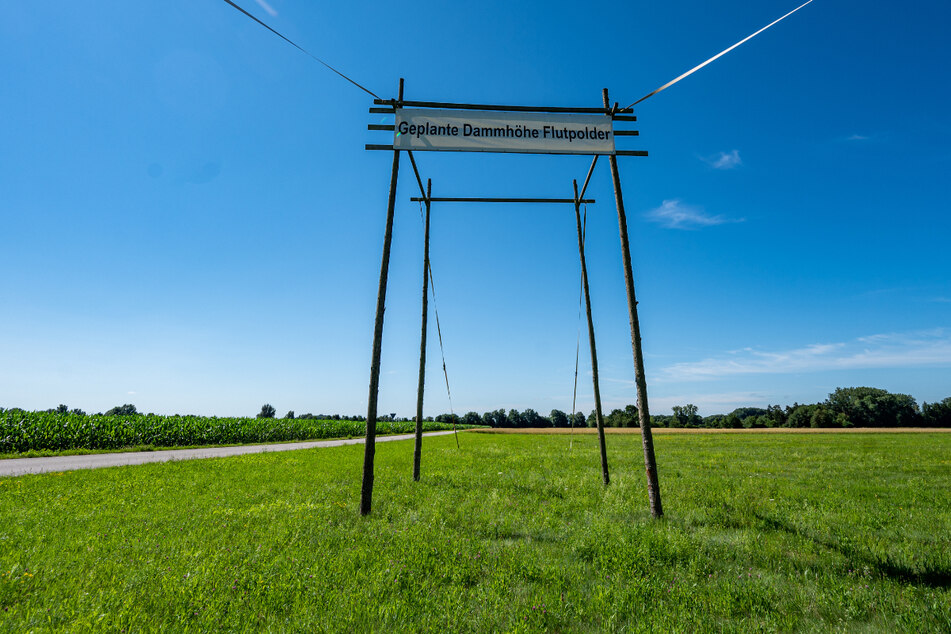 Ein Plakat mit der Aufschrift "Geplante Dammhöhe Flutpolder" in Wörth an der Donau zeigt, wie hoch die Dämme werden sollen.