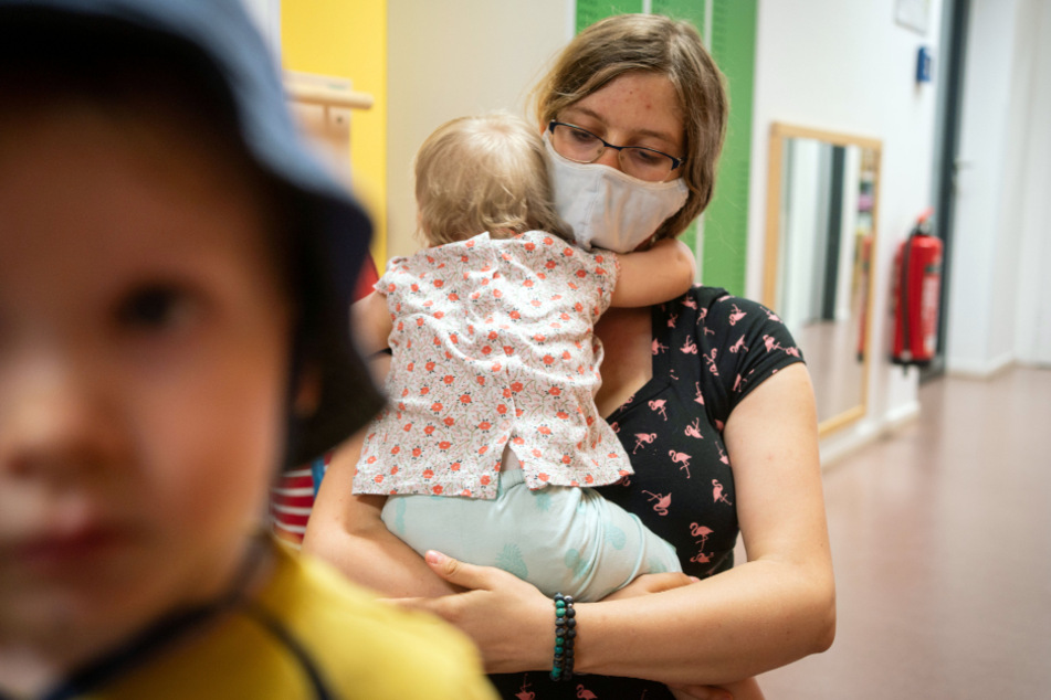 Hessen, Frankfurt/Main: Eine Erzieherin mit Mundschutz hält einen ihrer Schützlinge in einer Kindertagesstätte im Stadtteil Bornheim im Arm.
