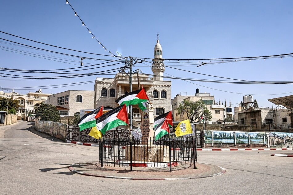 Palestinian flags flutter at the The Martyrs’ Monument, which bears the names of those killed by the Israeli army or settlers, in the village in Abu Falah, northeast of Ramallah, in the Israeli occupied West Bank, on March 12, 2026.