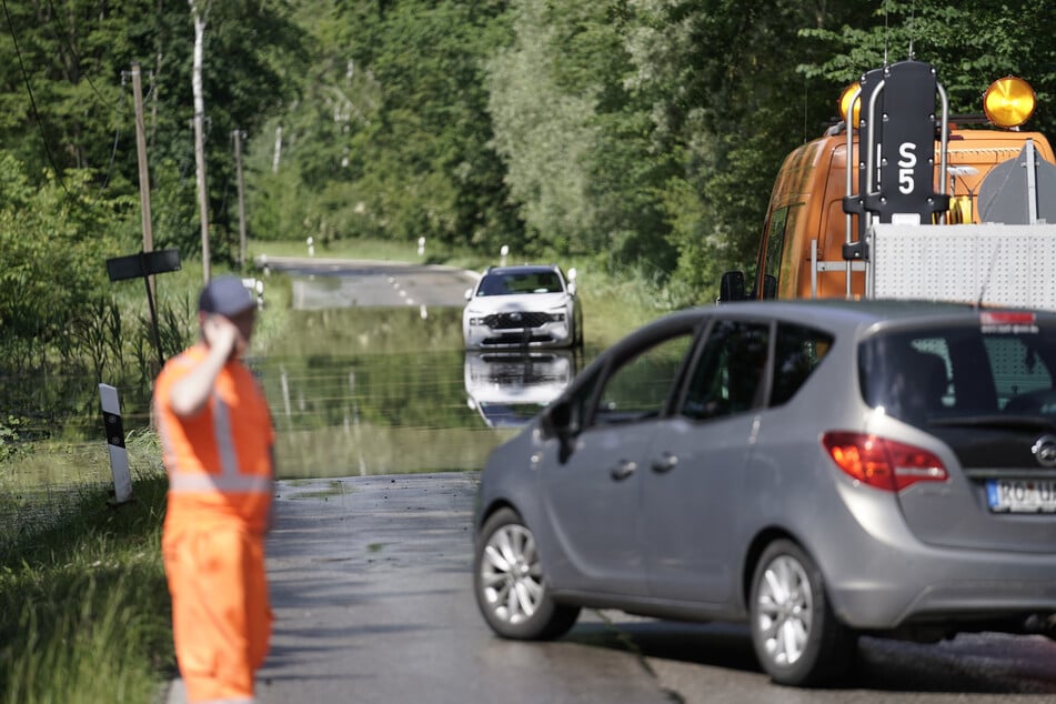 Fahrzeuge stehen vor einer überfluteten Straße im Landkreis Rosenheim