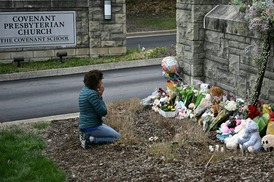 A woman sits in front of a makeshift memorial for victims outside the Covenant School building at the Covenant Presbyterian Church in Nashville, Tennessee.