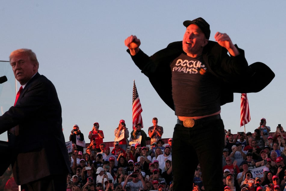 Elon Musk (r.) jumps into the air onstage with Donald Trump during a campaign rally in Butler, Pennsylvania, on October 5, 2024.