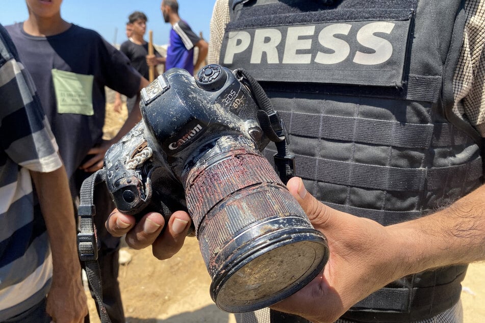 A member of the press holds the blood-covered camera of Palestinian photojournalist Mariam Dagga, who was killed in an Israeli strike on Nasser hospital in Khan Younis in the southern Gaza Strip, during her funeral on August 25, 2025.