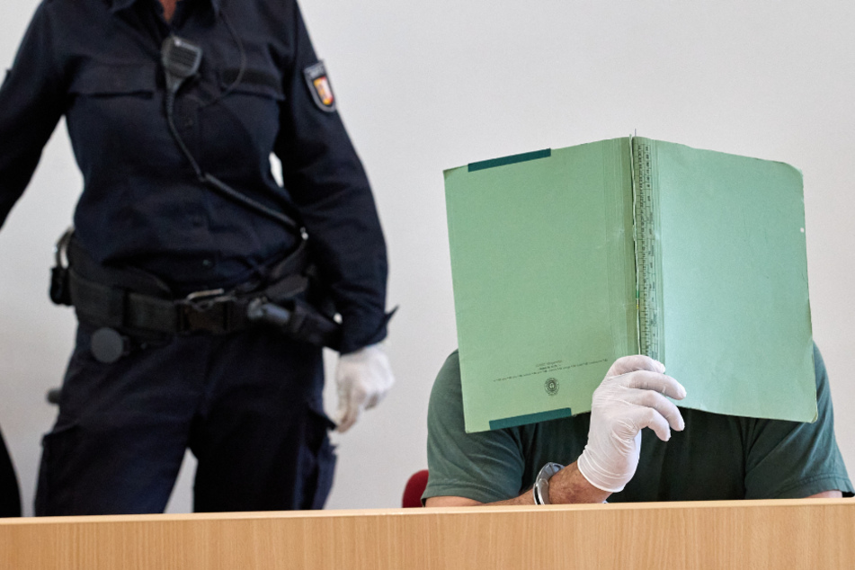Der Angeklagte versteckt sein Gesicht bei einem vorherigen Prozesstag hinter einem Aktendeckel.