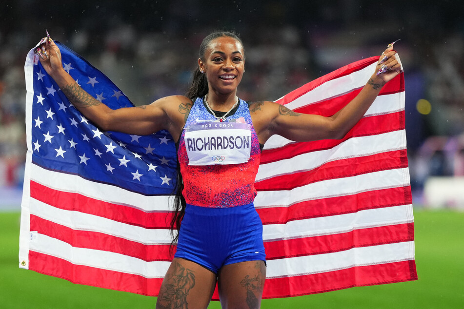 Sha'carri Richardson holds up the USA flag after winning her first Olympic medal in the 100m dash at the Paris Games.