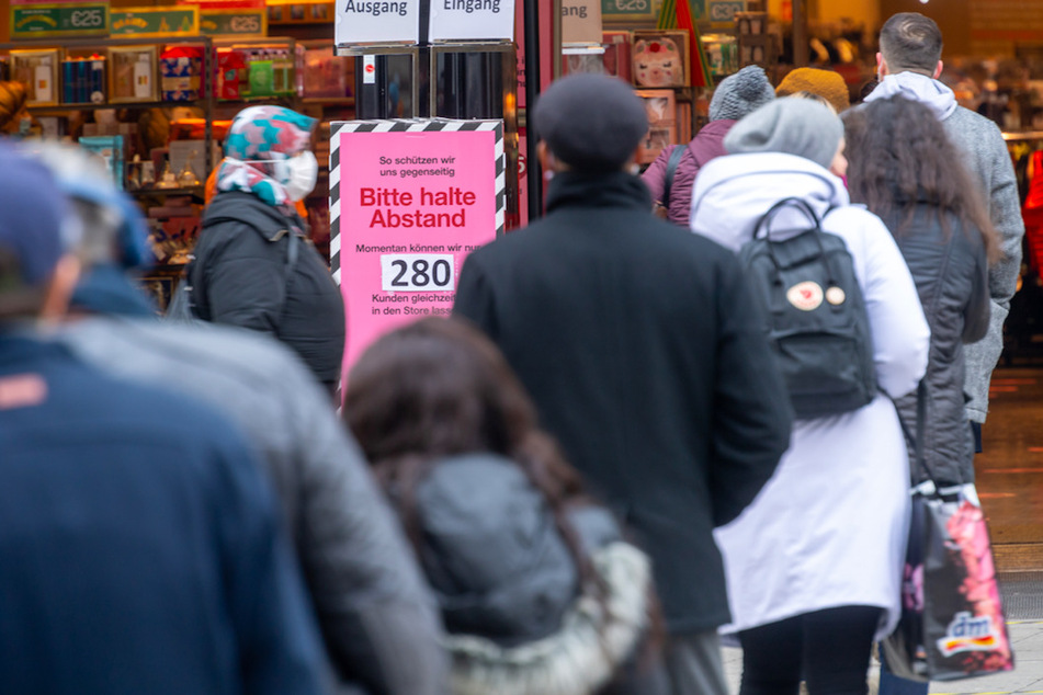 Ein Schild mit der Aufschrift "Bitte haltet Abstand - Momentan können wir nur 280 Kunden in den Store lassen" steht vor den Eingang eines Warenhauses in der Fußgängerstrasse in München.