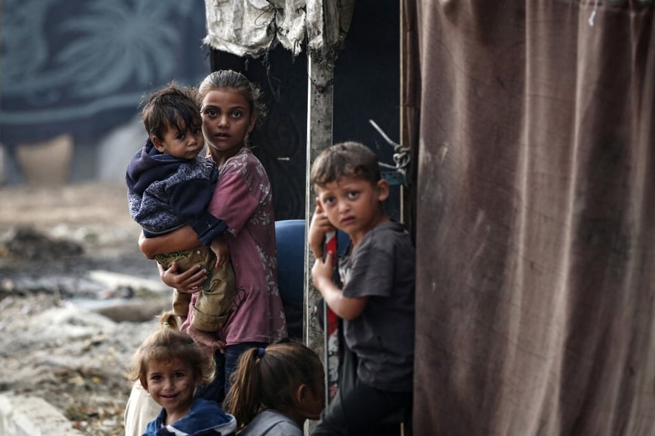 Palestinian children stand next to tents at a make-shift camp for the internally displaced in Deir al-Balah in the central Gaza Strip on October 17, 2024.