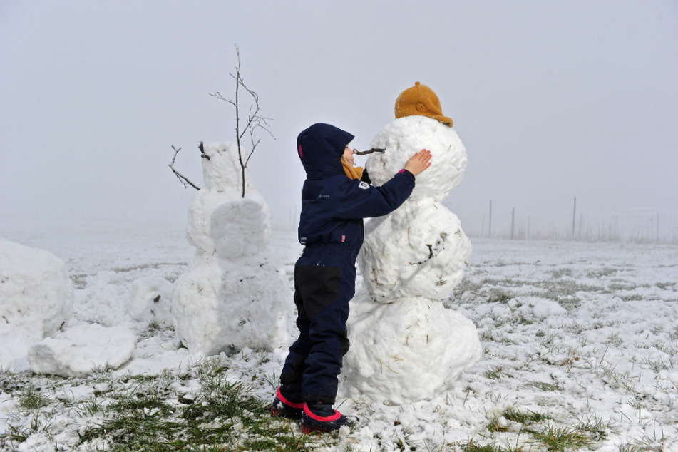 Die richtige Kopfbedeckung ist der kleinen Schneekünstlerin Martha-Magdalena (4) bei ihrem Schneemann wichtig - ebenso, dass er nicht frieren muss.