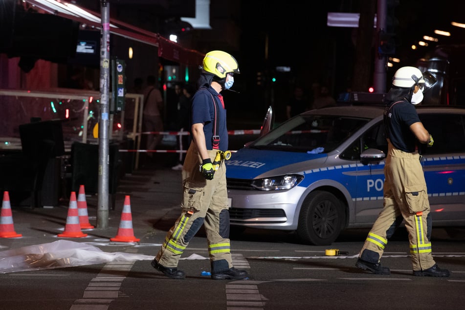 Feuerwehrleute gehen auf der Müllerstraße an Leitkegeln vorbei. In Berlin-Wedding sind am späten Sonntagabend vermutlich mehrere Schüsse gefallen.