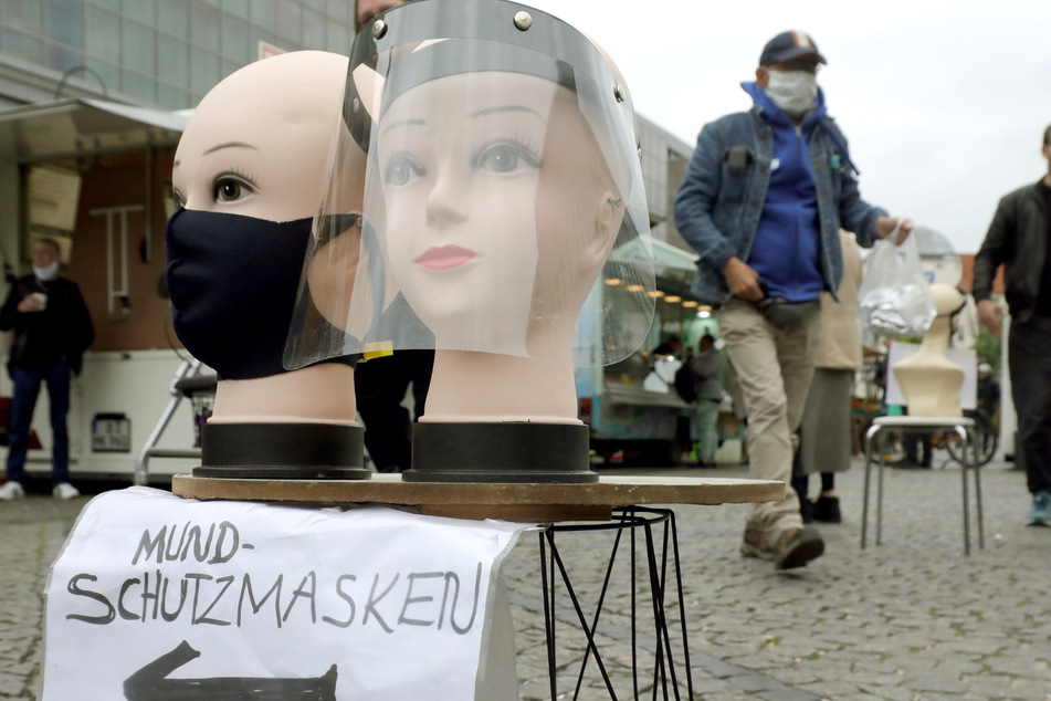 Menschen in Berlin gehen über einen Wochenmarkt auf dem Hermannplatz im Bezirk Neukölln, auf dem Mund- und Schutzmasken zum Kauf angeboten werden. (Archivbild)