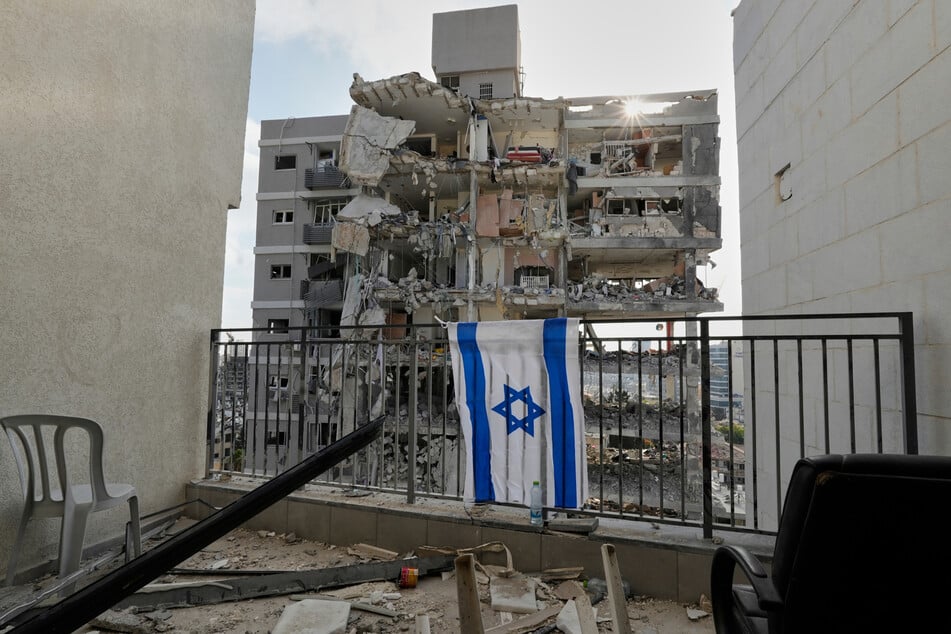 Eine israelische Flagge hängt am Sonntag in Bat Jam in Zentralisrael am Balkongeländer eines der Wohnhäuser, die durch einen iranischen Raketenangriff zerstört wurden.