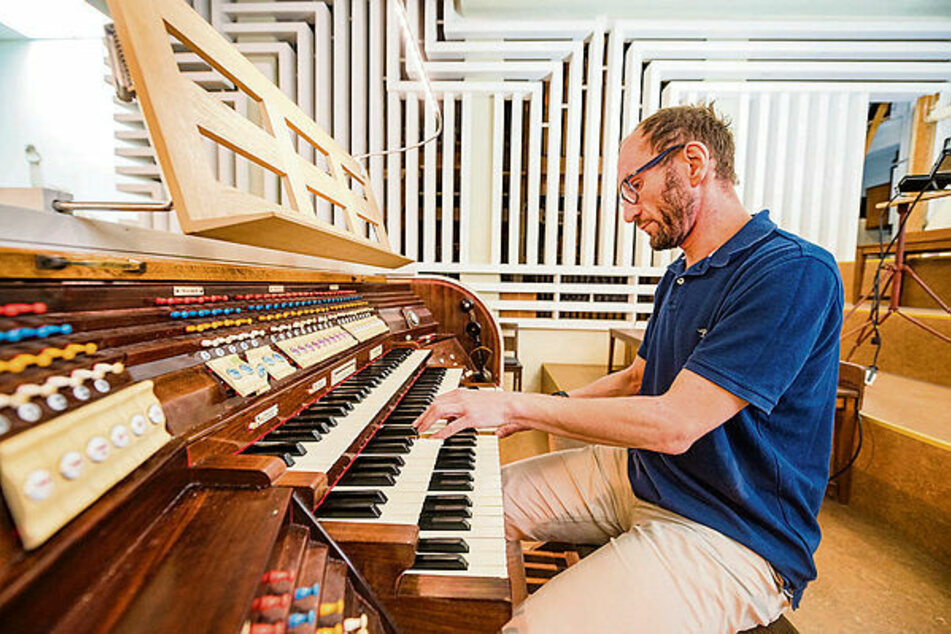 Organist Christian Otto am elektrischen Orgeltisch. Hinter ihm in der Wand die versteckten Orgelpfeifen.