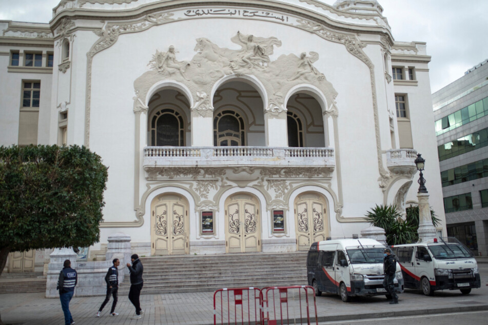 Ein Mitarbeiter der Sicherheitskräfte (r.) steht vor gepanzerten Autos auf der Avenue Habib Bourguiba im Zentrum der Stadt Tunis.