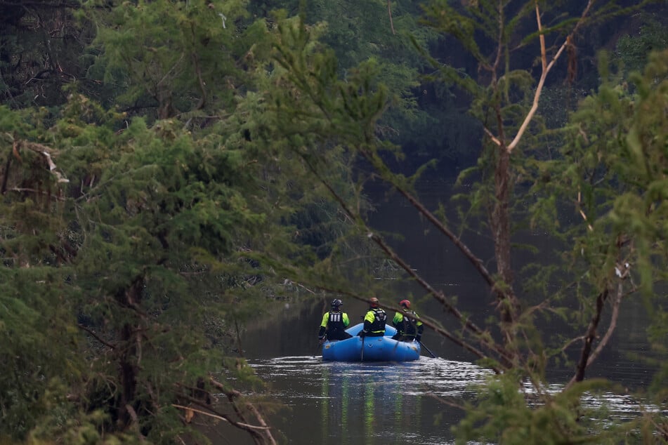 Rescuers paddle an inflatable boat as they search along a waterway following flash flooding in Kerrville, Texas, on July 6, 2025.