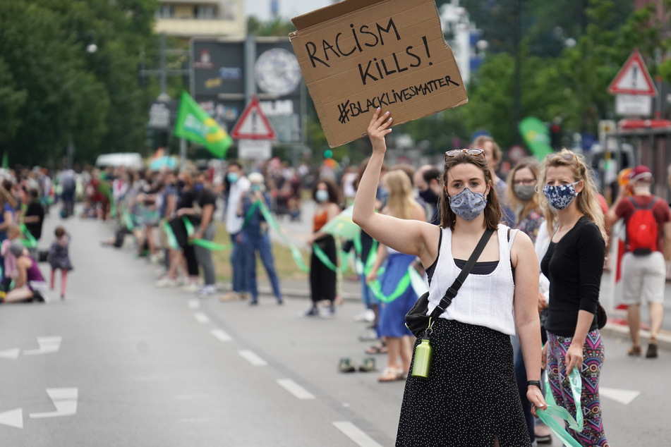Eine Teilnehmerin der Demonstration des Bündnisses "Unteilbar" gegen soziale Ungerechtigkeiten und Rassismus trägt ein Plakat mit der Aufschrift "Racism Kills! #Blacklivesmatter".