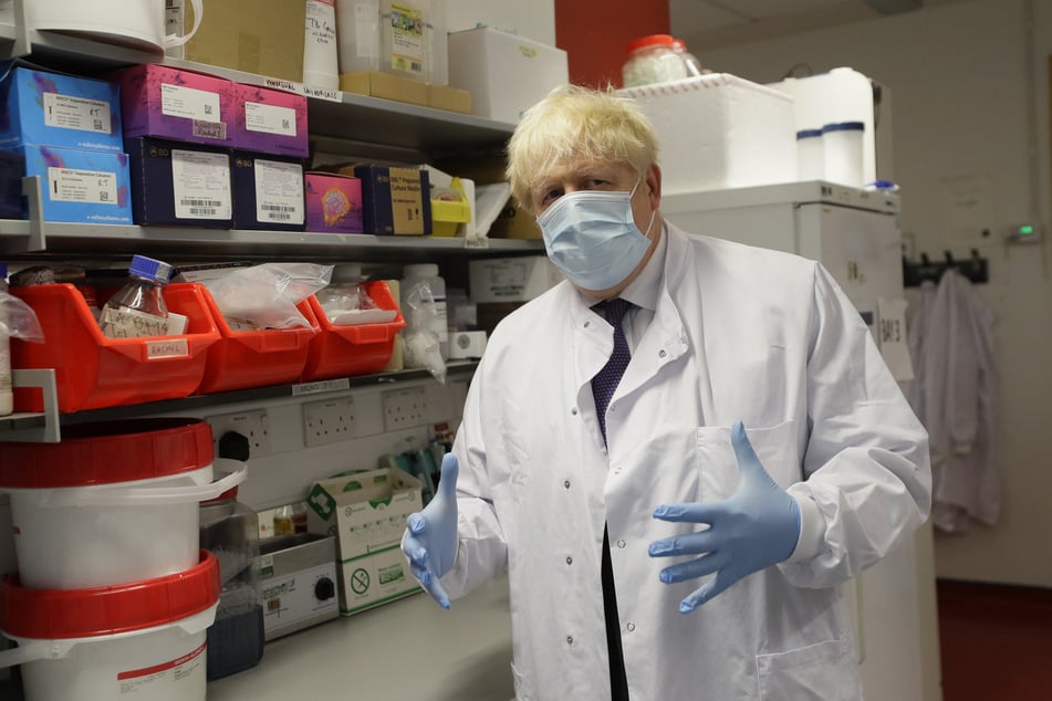 Boris Johnson, Premierminister von Großbritannien, gestikuliert mit seinen Händen und trägt Schutzkleidung und Maske,