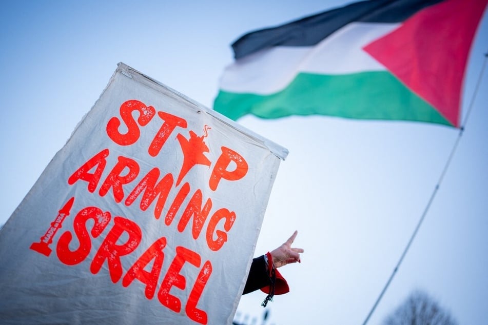 Protestors raise a sign reading "Stop Arming Israel" outside the White House in Washington DC.