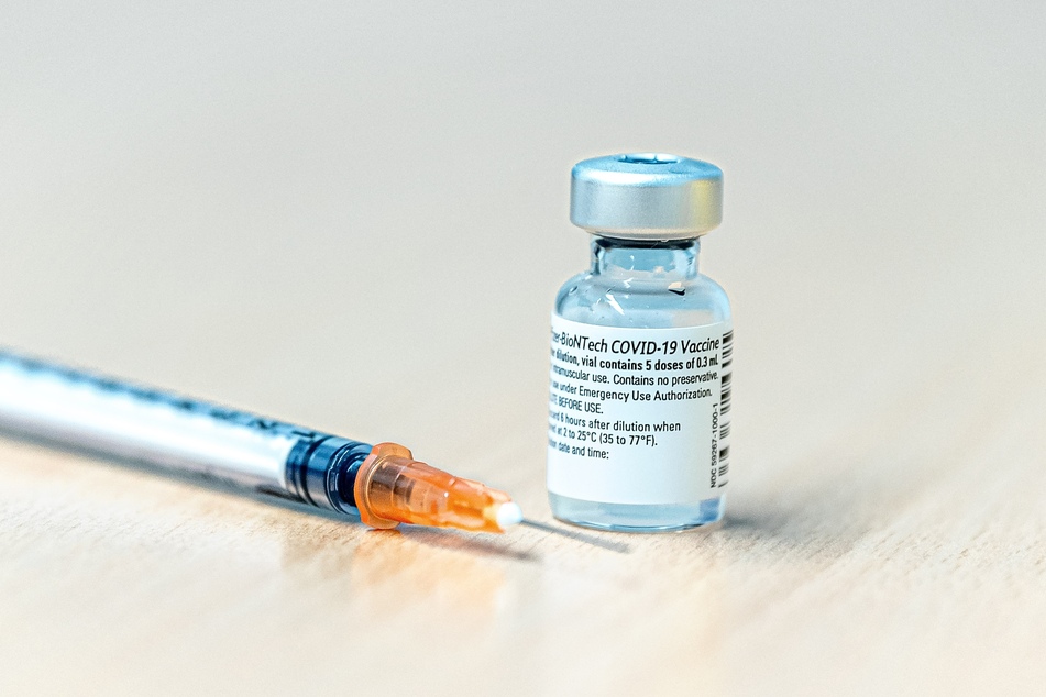 Eine Dosis mit dem Covid-19 Pfizer-Biontech Impfstoff steht neben einer Spritze auf einem Tisch im Impfzentrum.