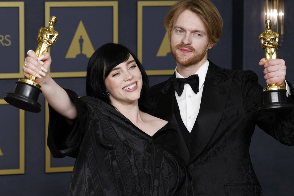Billie Eilish and Finneas O'Connell hold up their Best Original Song Oscars for No Time To Die.