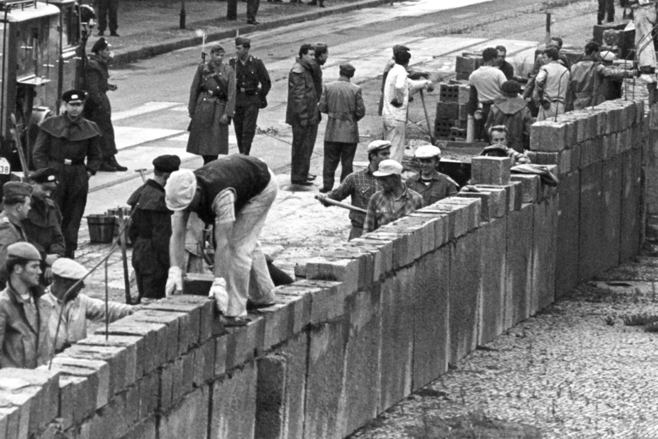 1961: Unter der Aufsicht von bewaffneten Volkspolizisten wird an der sowjetisch-amerikanischen Sektorengenze am Potsdamer Platz die Mauer errichtet.