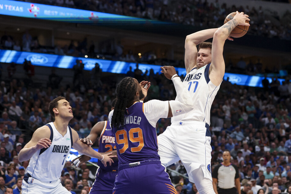 Mavericks guard Luka Doncic grabs a rebound over Phoenix Suns forward Jae Crowder.
