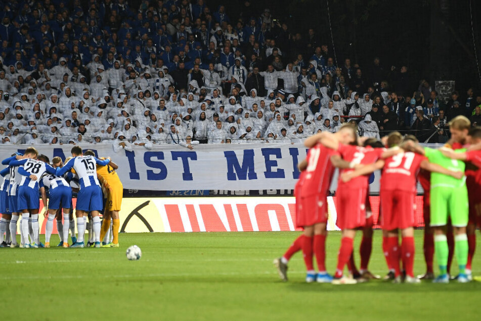 Die Spieler von Hertha (l) und Unions schwören sich vor dem Anpfiff auf das Derby ein.