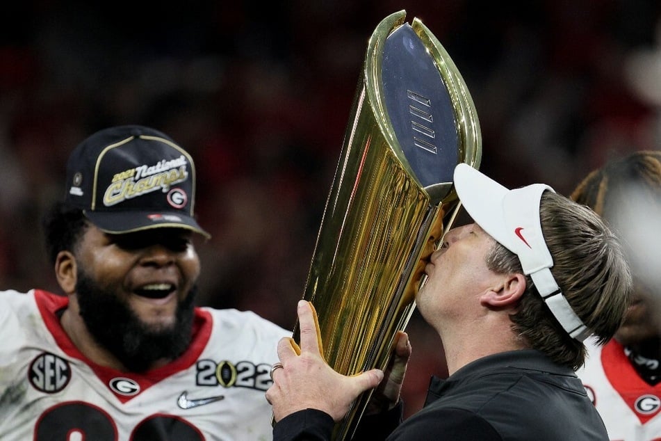 Head Coach Kirby Smart (r.) of the Georgia Bulldogs kissed the National Championship trophy after the Georgia Bulldogs defeated the Alabama Crimson in January.