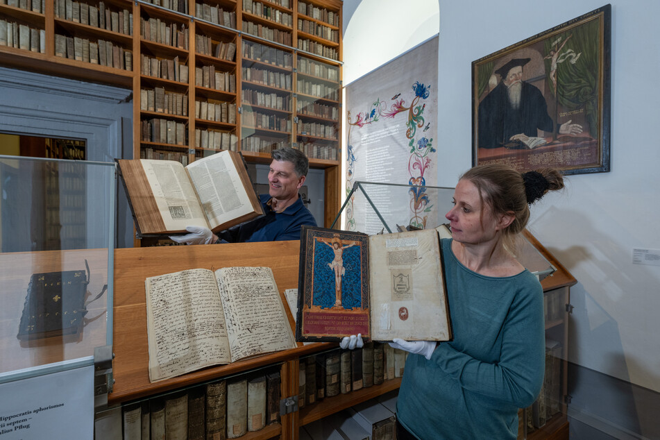 Cordula Strehl, Bibliothekarin, und Joachim Säckl, Projektkoordinator, zeigen in der Bibliothek des katholischen Bischofs Julius Pflug (1499 - 1564) im Torhaus des Schlosses Zeitz zwei wertvolle theologische Bücher.