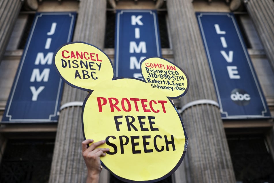 A demonstrator waves a "Protect Free Speech" sign during a protest against the suspension of the Jimmy Kimmel Live! show in Los Angeles, California, on September 22, 2025.