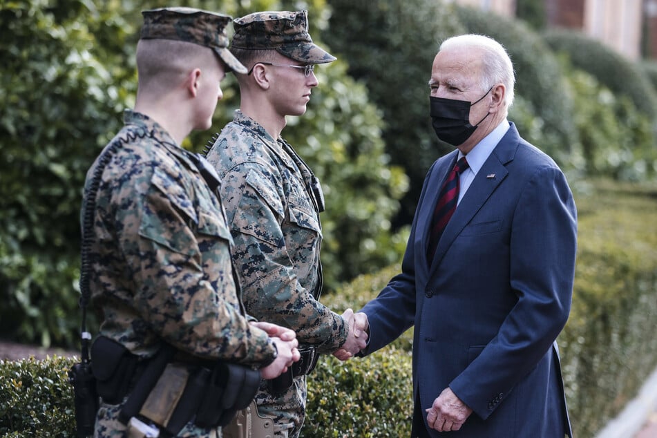President Joe Biden shaking hands with a Marine outside the Marine barracks in Washington DC.