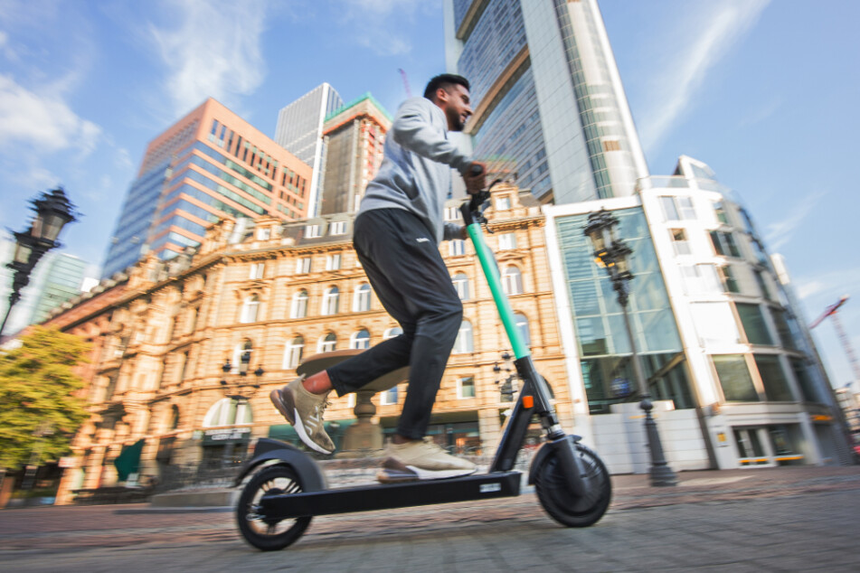 Ein Mann fährt mit einem E-Tretroller durch Frankfurt am Main.