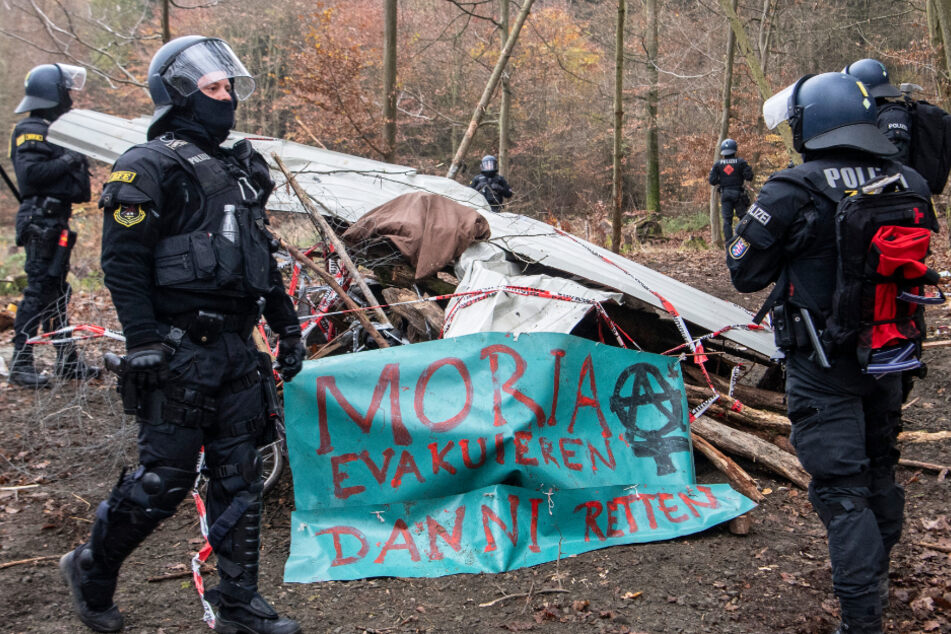 Polizisten stehen am zweiten Tag des Großeinsatzes während der Räumung von Barrikaden im Dannenröder Wald neben einem Banner.