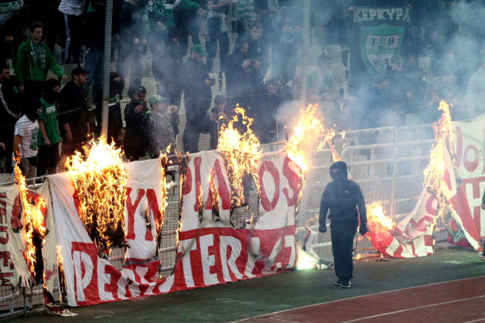 Vermummte Fans verbrennen während des Derbys zwischen Panathinaikos und Olympiakos Piräus ein Banner ab. (Archivfoto)