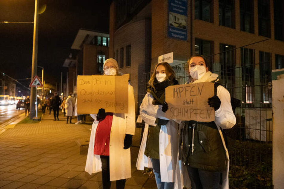 Mit Sprüchen wie "Impfen statt Schimpfen" positionierten sich Medizinstudentinnen und Krankenhausmitarbeiter vor der Dresdner Uniklinik, um gegen "Querdenker" zu protestieren.