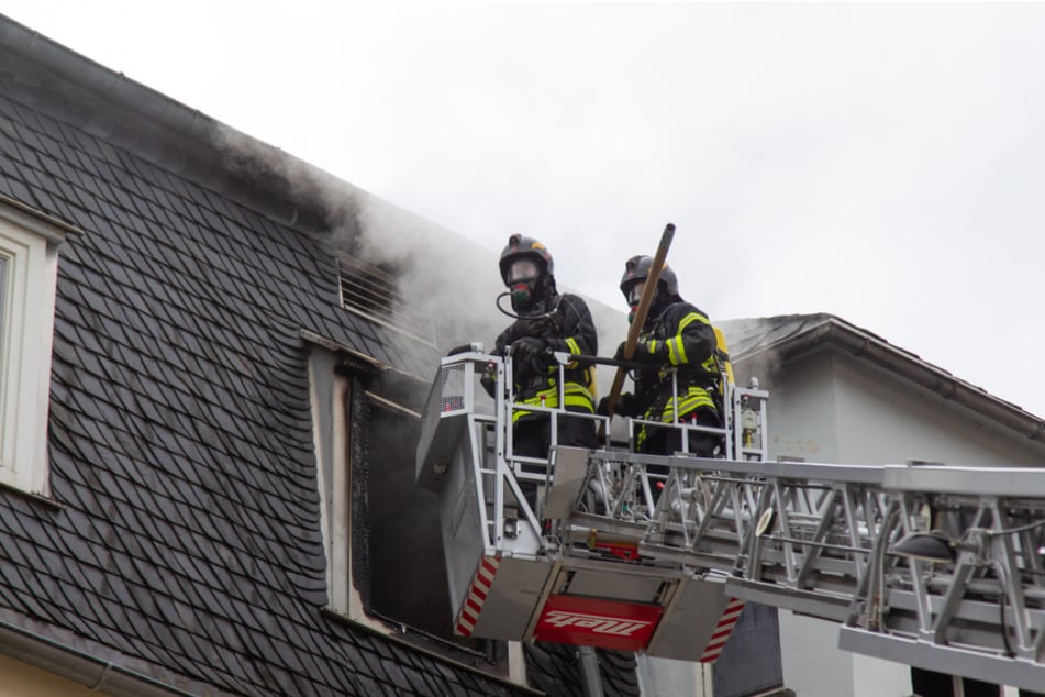 Aus dem Fenster eines Mehrfamilienhauses dringt Rauch.