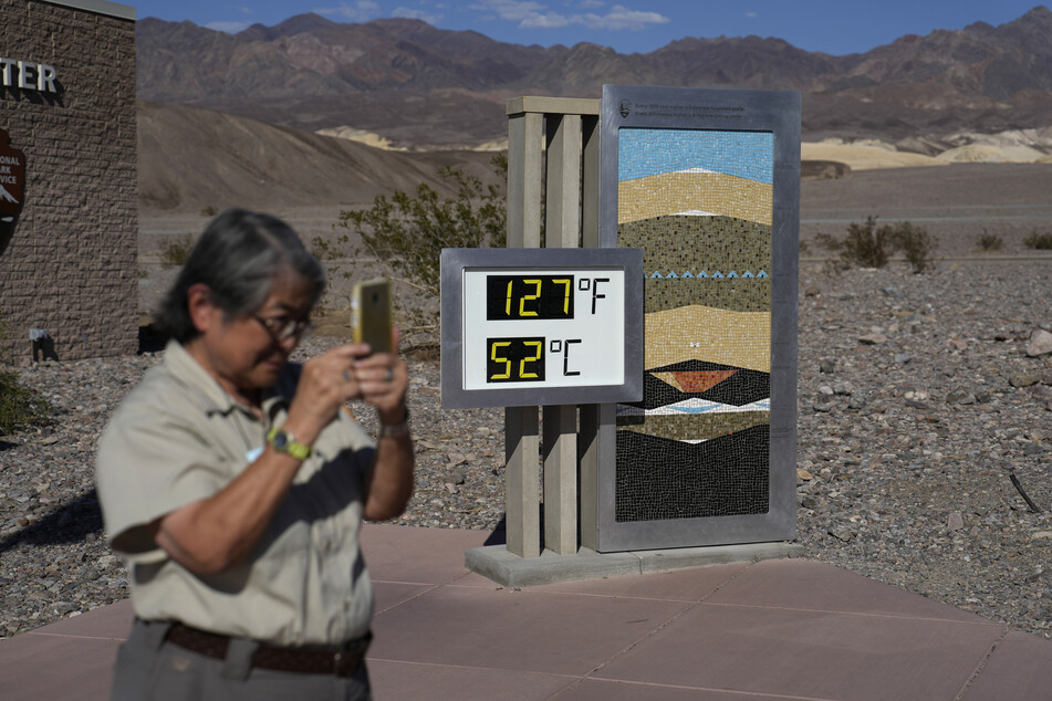 Eine Park-Besucherin steht an einem Thermometer im Furnace Creek Visitor Center im Death Valley National Park. Das Thermometer ist nicht offiziell, aber ein beliebter Fotopunkt.