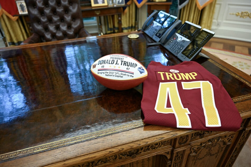 A football and a jersey honoring the 2027 NFL Draft, on the Resolute desk in the Oval Office as US President Donald Trump announces that Washington, DC, will host the 2027 NFL Draft, in the Oval Office of the White House in Washington, DC, on Monday.