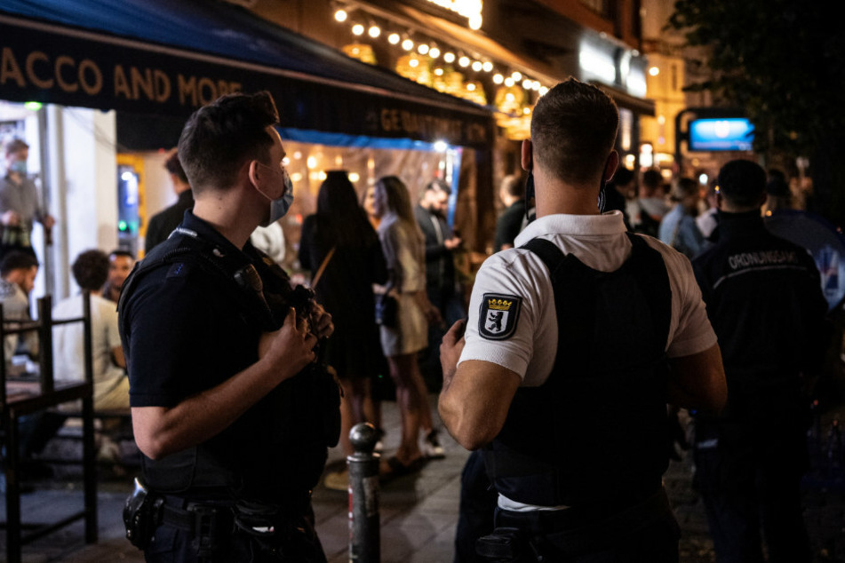 Ein Polizeibeamter und ein Mitarbeiter des Ordnungsamtes stehen vor einem Lokal.